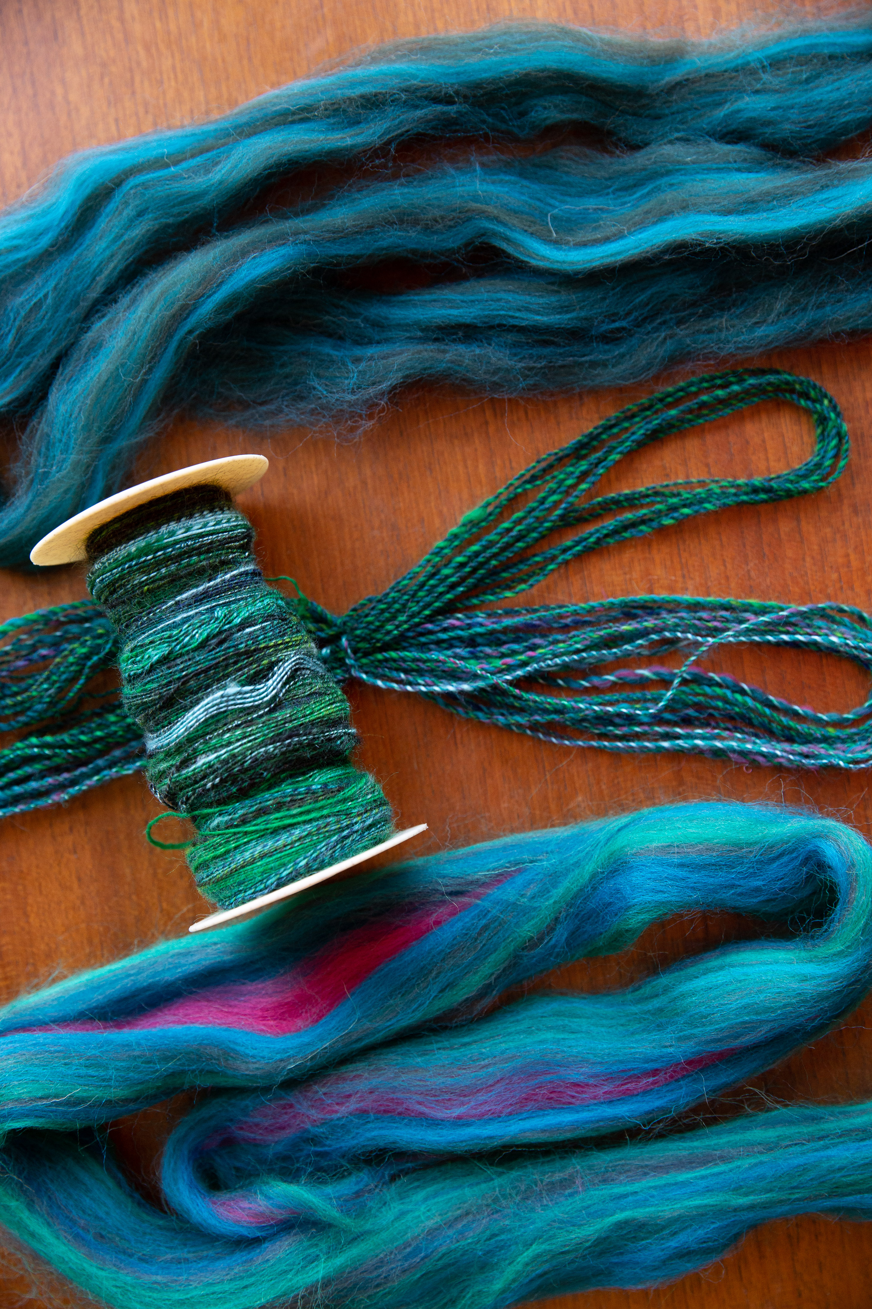 a bobbin of handspun single with two rovings in teal and turquoise